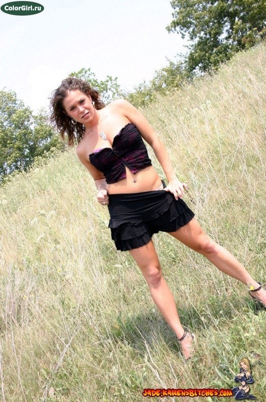 Симпатичная девушка в черной юбке позирует в поле